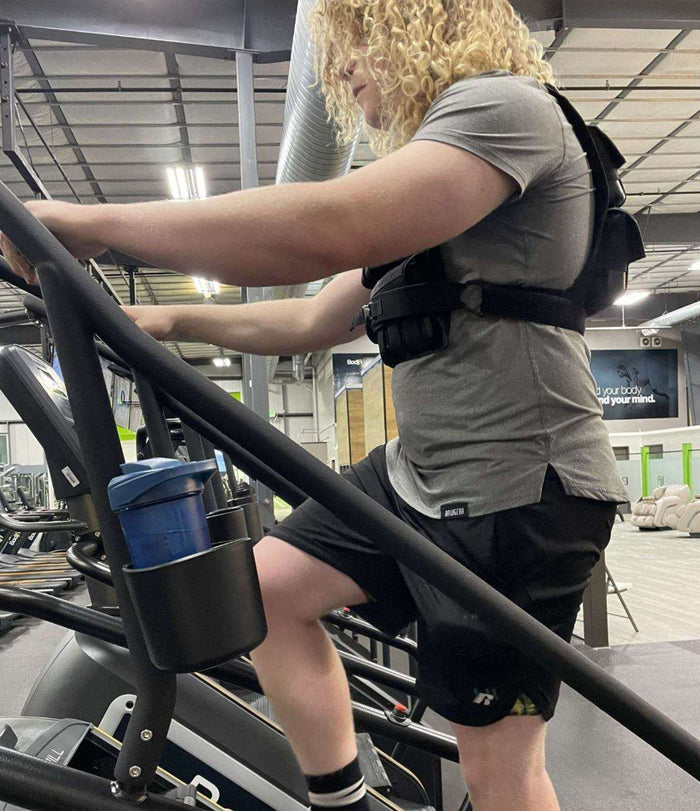 Young man training on stair machine with weight vest for extra resistance, building strength and endurance to prepare for a firefighting job