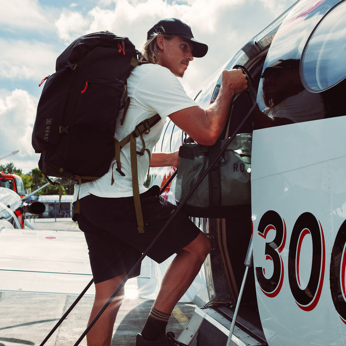 Man wearing black Roark 5 Day Mule 55L backpack boarding RV, lifestyle shot in outdoor travel setting