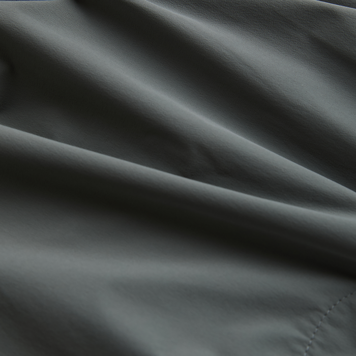 Close-up texture of a premium grey silk material with silver linens, evoking the quality and durability needed for adventure and travel gear.
