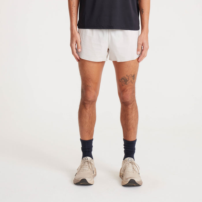 Front view of lightweight beige running shorts with breathable fabric and minimalist logo detail.