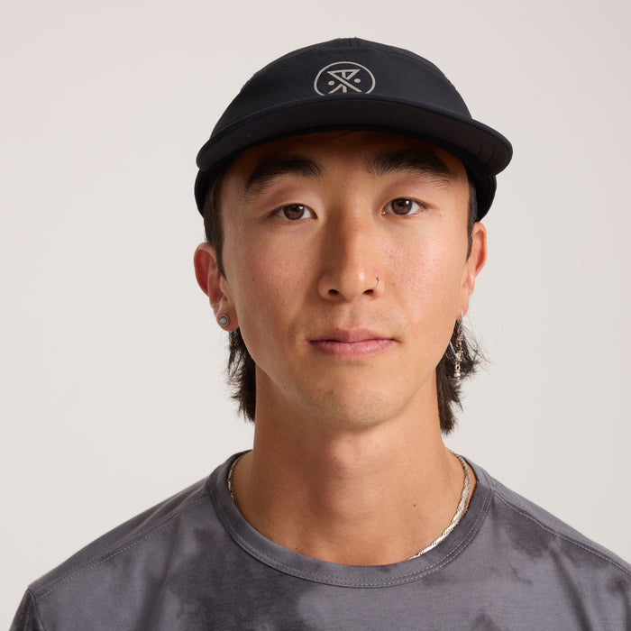 Model wearing a versatile black baseball cap designed for outdoor adventures and travel, showcasing Roark's commitment to durable headgear for active lifestyles.