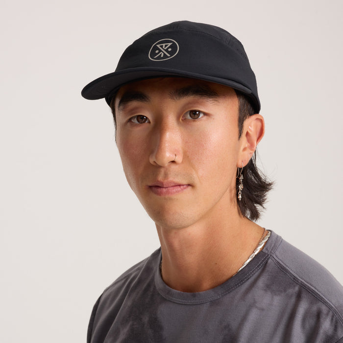 Model sporting a versatile black baseball cap designed for outdoor adventures and travel, from Roark's latest collection.
