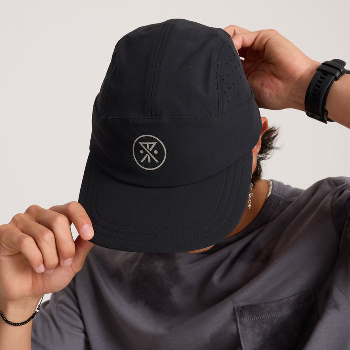 Stylish adventurer wearing a versatile Roark black baseball cap perfect for outdoor activities and travel.