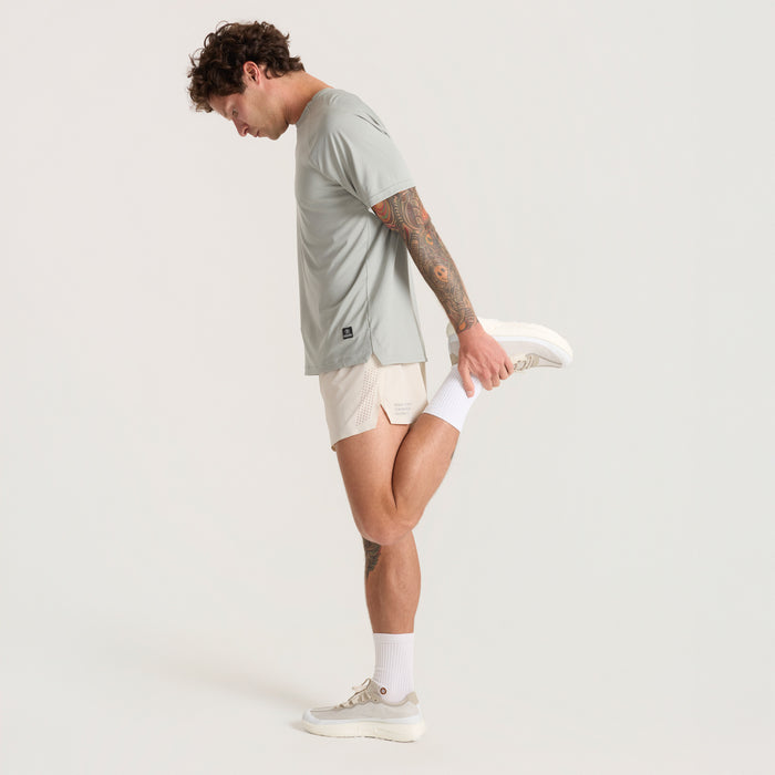 Active male model showcasing knee-length Roark sportswear shorts, ideal for adventure and outdoor activities, with focus on knee and calf flexibility.