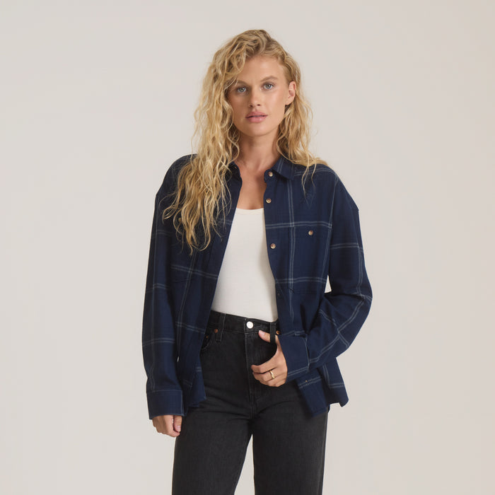 Amberley Light Long Sleeve Flannel in deep navy plaid, worn open over white tank top with black jeans on model