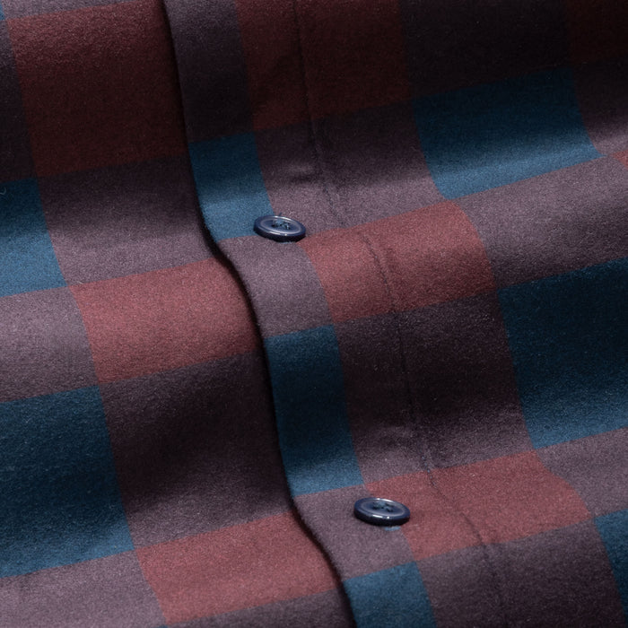 Close-up of a mulberry plaid fabric with a button, showing a checkered pattern in shades of red and blue.