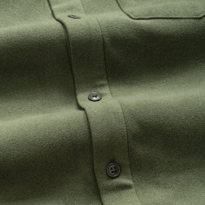 Close-up of a pine green flannel shirt with buttons on a matching fabric background
