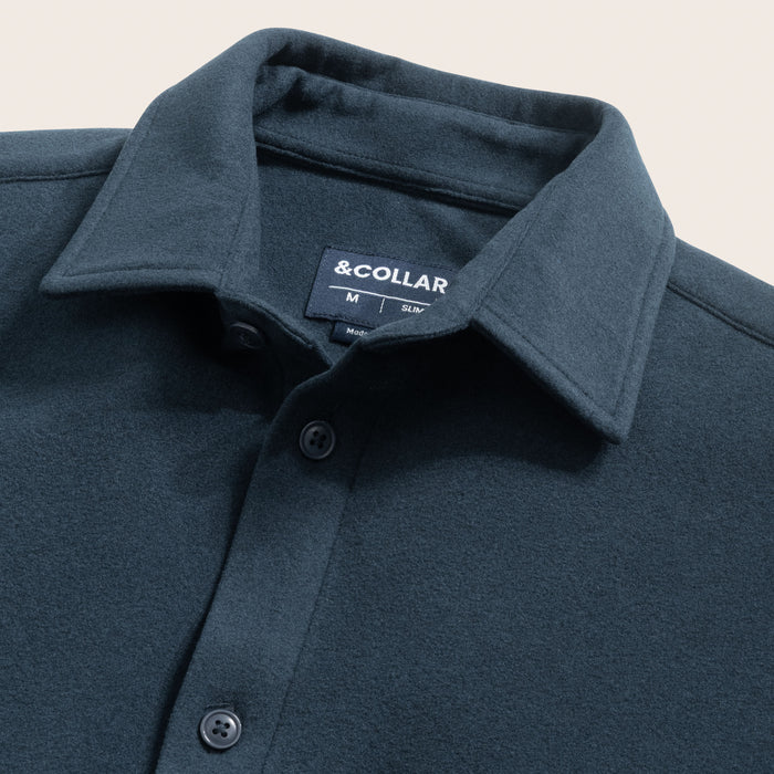 Close-up of a storm blue flannel button-up shirt with collar and brand label on a light gray background