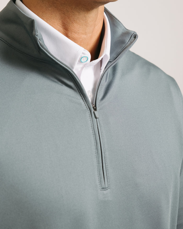Detail shot of steel gray long-sleeve quarter zip over a white shirt with a visible brand logo.