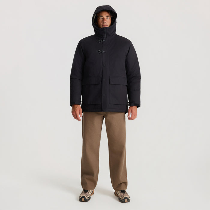 Black Axeman parka jacket on model with hood up, toggle fastenings, and patch pockets, worn with tan pants