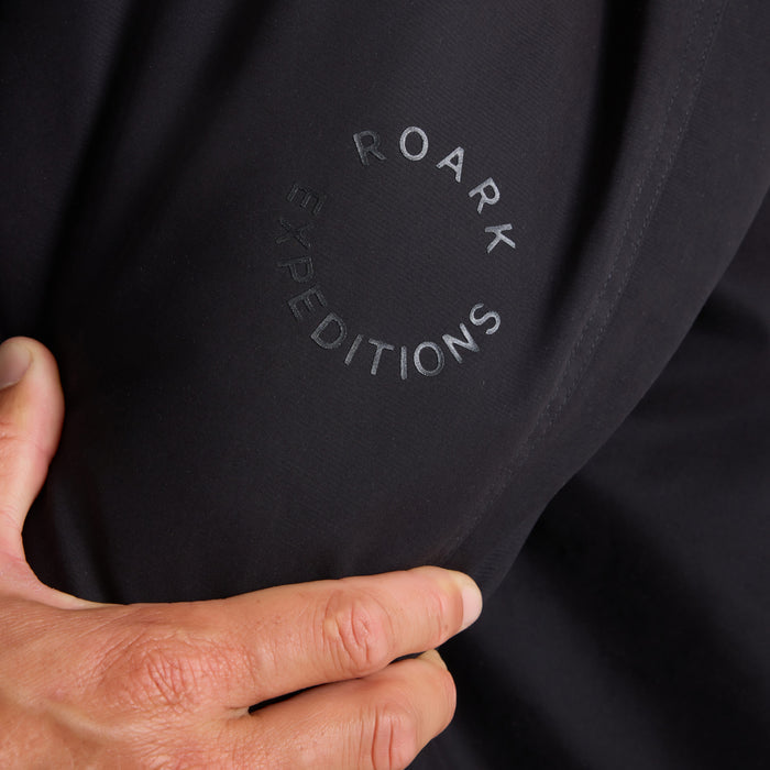 Black Roark Axeman Parka jacket with embroidered "Roark Limited Editions" text visible on fabric, held in hand detail shot