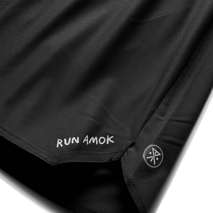 A man wearing the Roark Baja 5" Shorts in Black 2 while relaxing on a beach, demonstrating their versatility for casual outings.