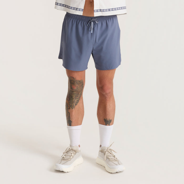 Model wearing versatile Roark boardshorts ideal for adventure and travel, highlighted by casual Bermuda style and active fit