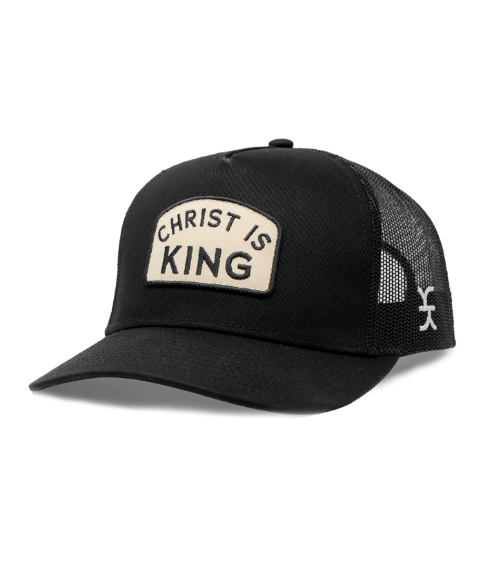 Black cap with 'Christ is King' patch on a white background