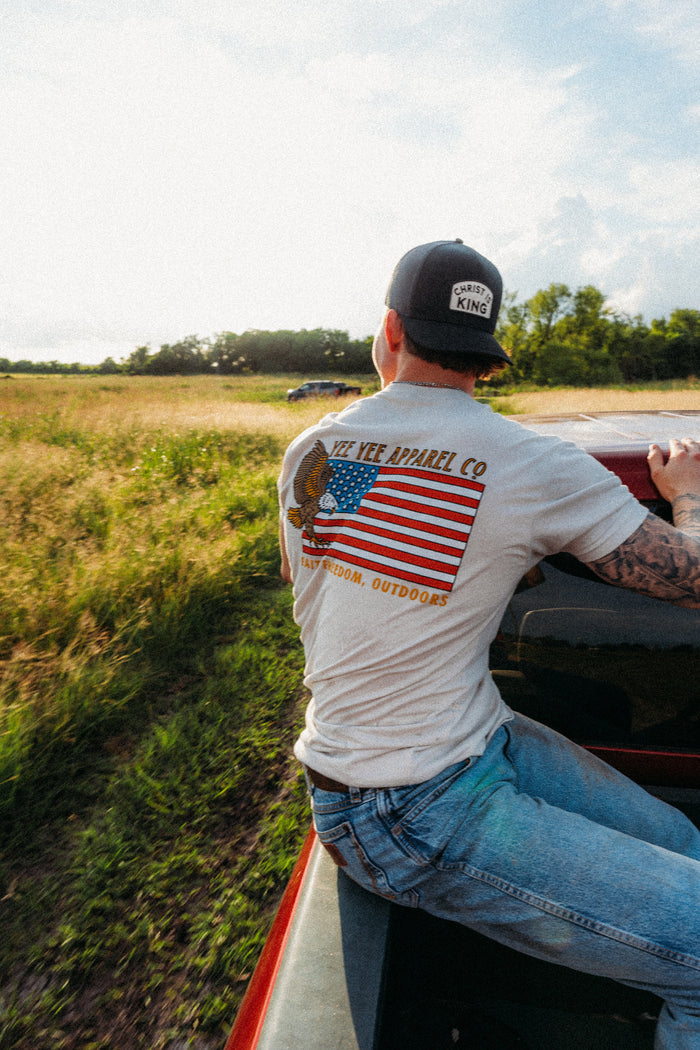 Man with tattooed arm climbing into a truck in a field