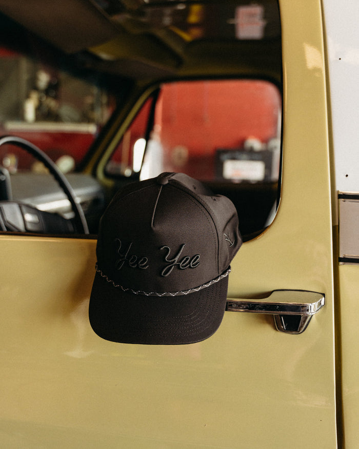 Black cap with 'Yee Yee' text on a car door handle