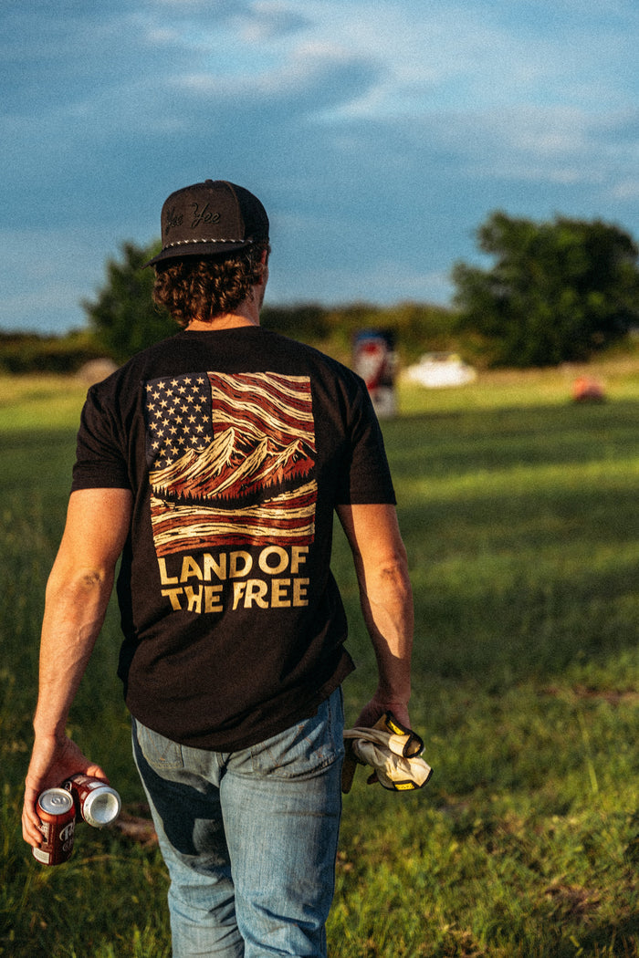 Man wearing a 'Land of the Free' t-shirt in a field
