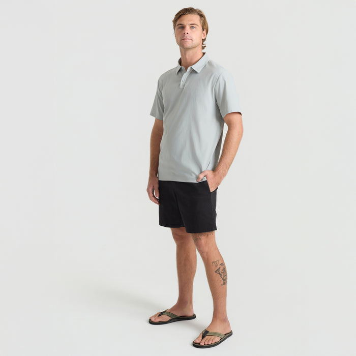 Man wearing a gray Roark polo shirt and shorts, ready for an outdoor adventure
