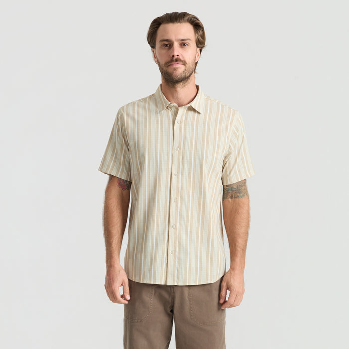 Close-up of a stylish beige dress shirt featuring detailed stitching on the collar, button line, and pocket, perfect for outdoor and travel adventures.