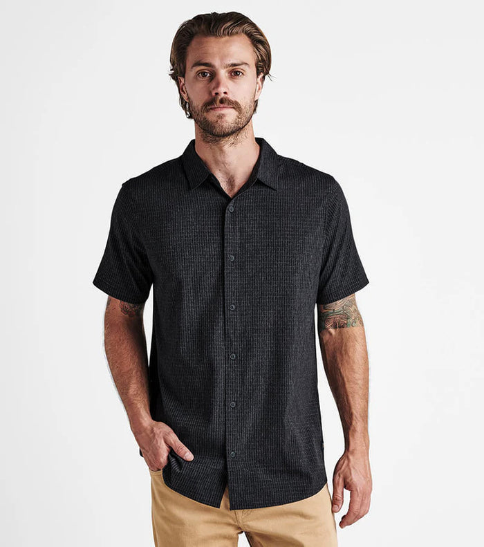 Close-up of a versatile black dress shirt tailored for adventure, featuring detailed stitching on sleeves, collar, and buttons, ideal for travel and outdoor activities.