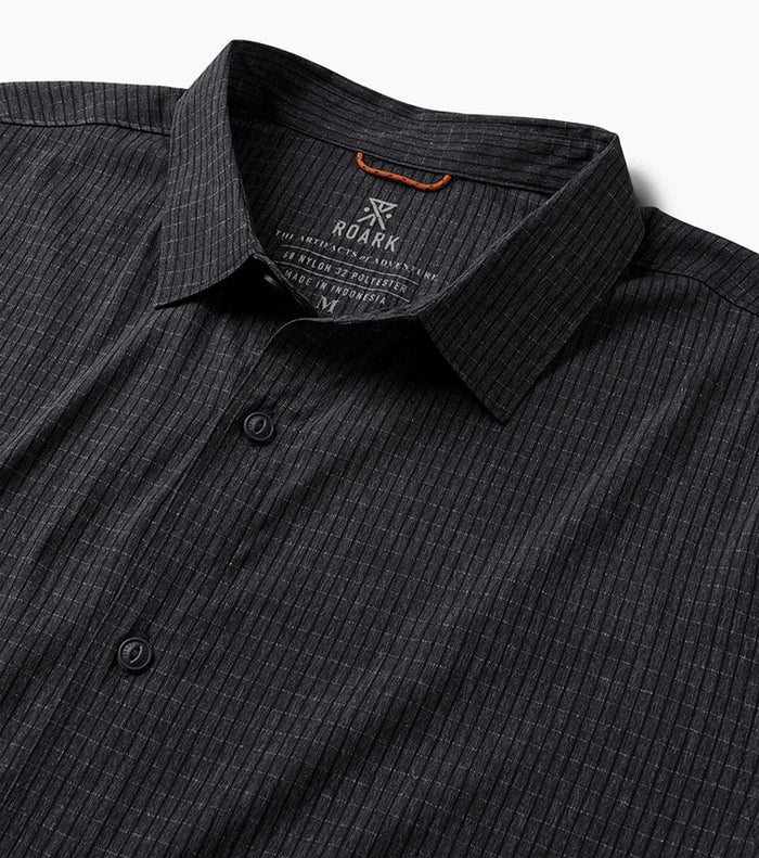Close-up view of a stylish black dress shirt featuring detailed design with visible collar, buttons, and sleeves, embodying Roark's commitment to adventure-ready fashion.