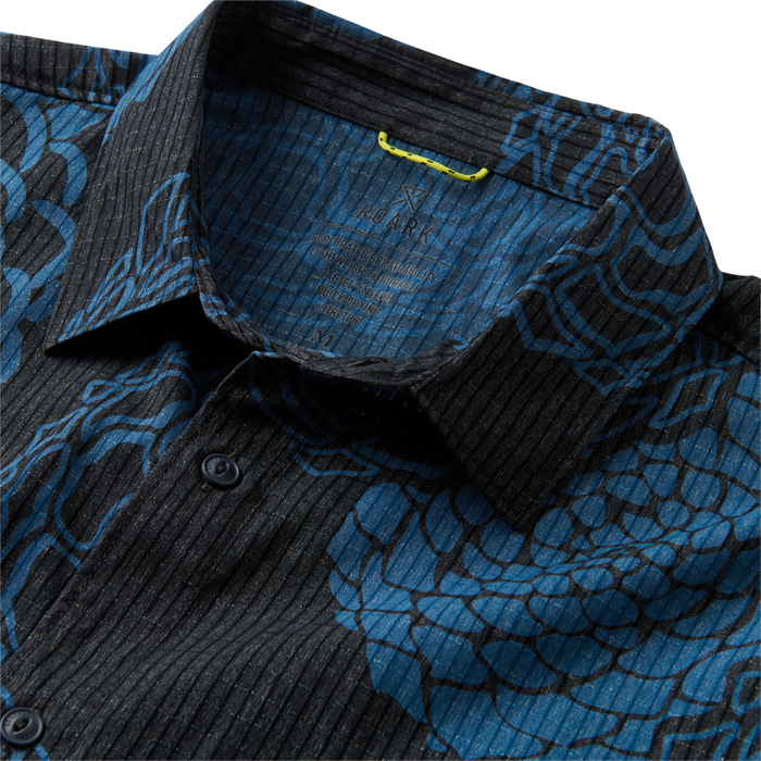 Detail view of a textured blue shirt with visible collar, sleeves, and buttons highlighting the durable fabric suitable for outdoor and travel adventures.