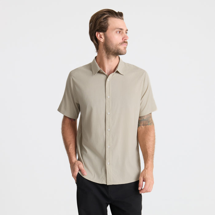 Close-up view of a versatile Roark adventure dress shirt featuring detailed stitching on the sleeve, collar, and pocket, with visible buttons for a secure fit.