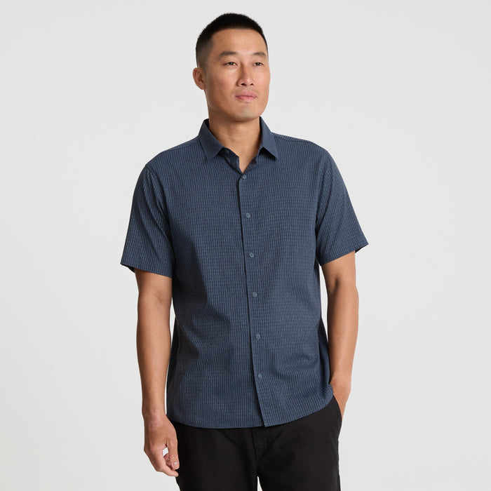 Close-up of a navy Roark adventure dress shirt highlighting the detailed sleeve, collar, and button design, crafted for travel and outdoor activities.