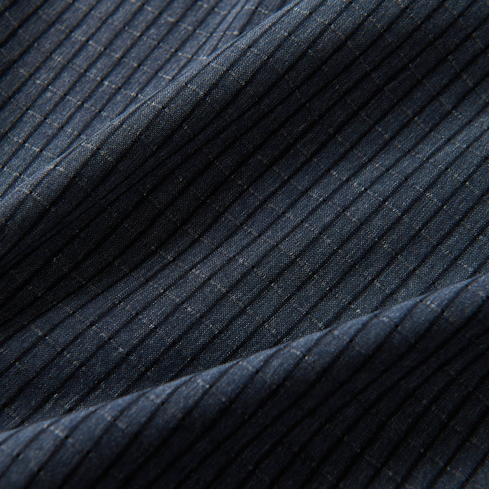 Close-up of textured blue woven fabric, highlighting details in denim and linen textures, conveying a sense of rugged outdoor adventure and travel.
