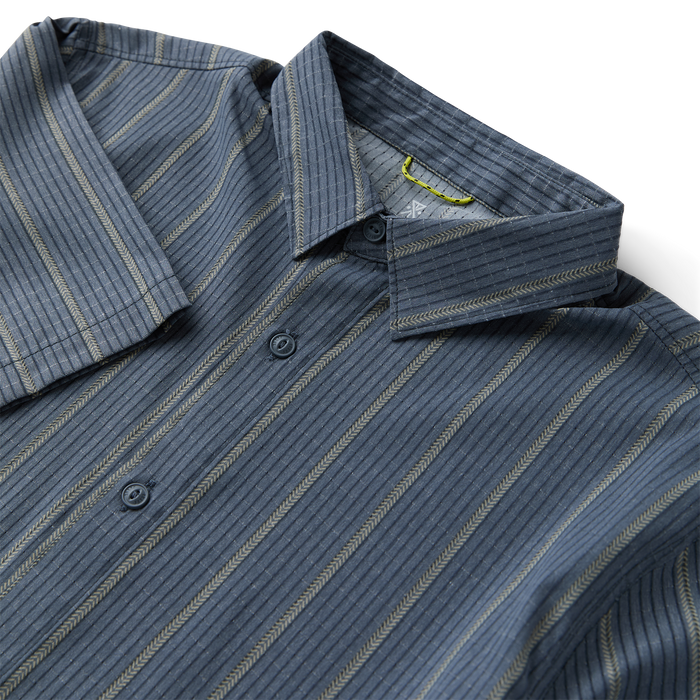 Close-up of a rugged Roark denim dress shirt featuring distinctive buttons and a sturdy collar, ideal for travel and adventure.
