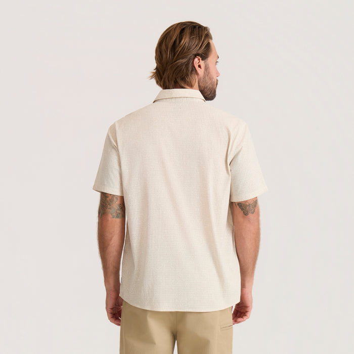 Cream textured short-sleeve shirt on man shown from back, paired with khaki pants, displaying collar and relaxed fit