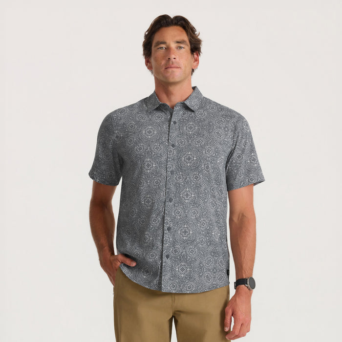 Charcoal gray short-sleeve shirt with geometric print pattern worn by man with khaki pants against neutral background