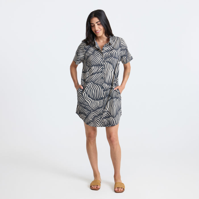 Model in a versatile Roark gray one-piece garment, styled as both day dress and nightwear, in an outdoor photo shoot setting, embodying adventure and travel.