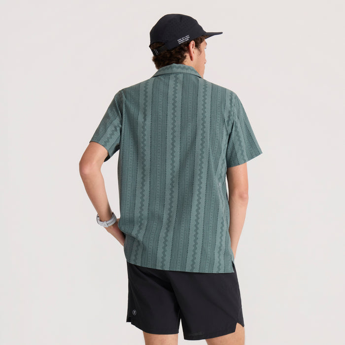 Slate green short-sleeve button-up shirt with vertical texture pattern worn by model from back view with black cap