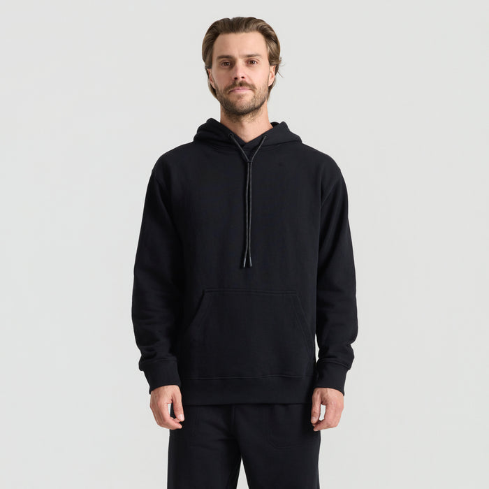 Man standing in adventure-ready pose wearing a black hooded jacket from Roark, embodying the spirit of outdoor exploration.