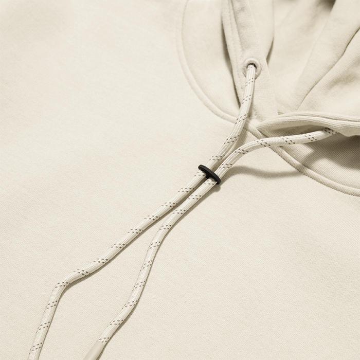Cream-colored bolo fleece hoodie drawstring detail with black adjustable stopper on beige background flat lay
