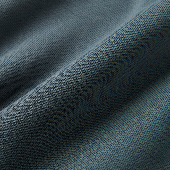 Close-up of textured grey woven denim fabric highlighted by silver threads, embodying Roark's commitment to durable and functional adventure wear.