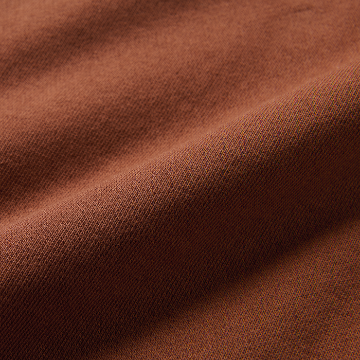 Detailed texture of orange and brown woven fabric, evoking the ruggedness of outdoor adventure gear by Roark.