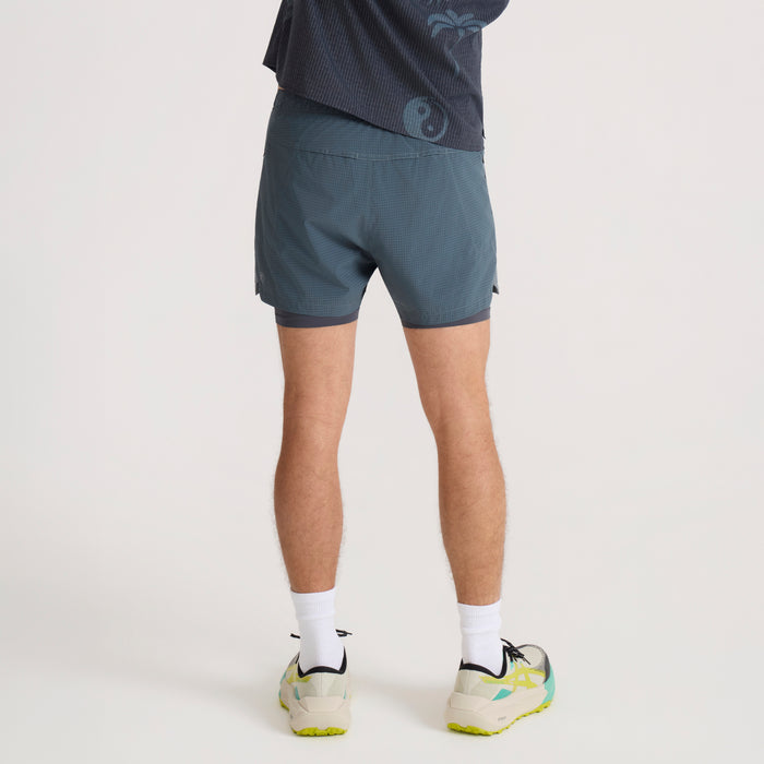 Slate blue Bommer 3.5" shorts on model from behind, paired with white socks and trail running shoes