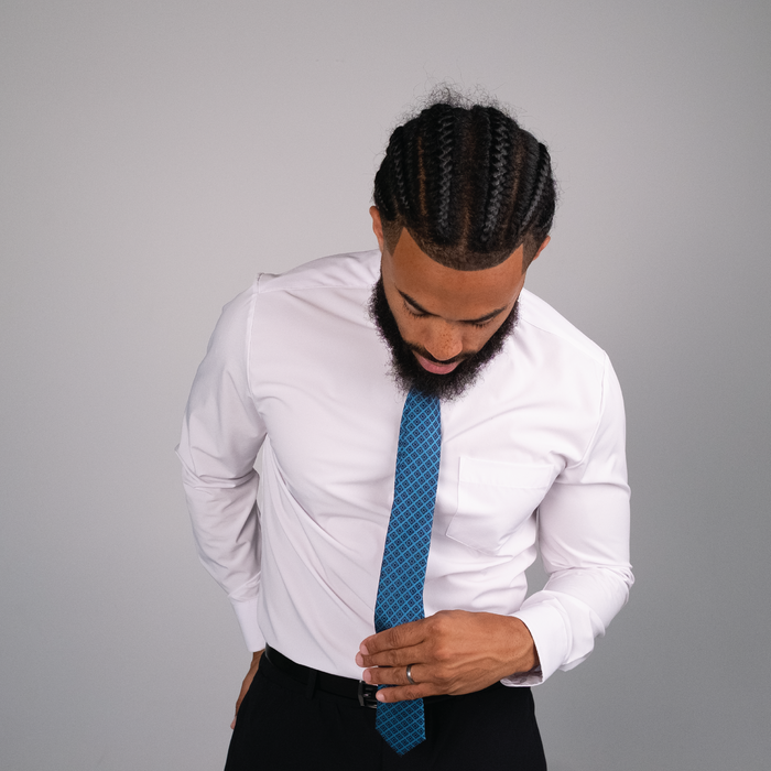 Dark blue diamond icon patterns on a light sky blue tie on white dress shirt.