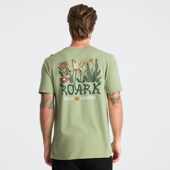 Active shirt displayed amidst wildflowers and fresh produce, capturing an essence of outdoor adventure and travel.