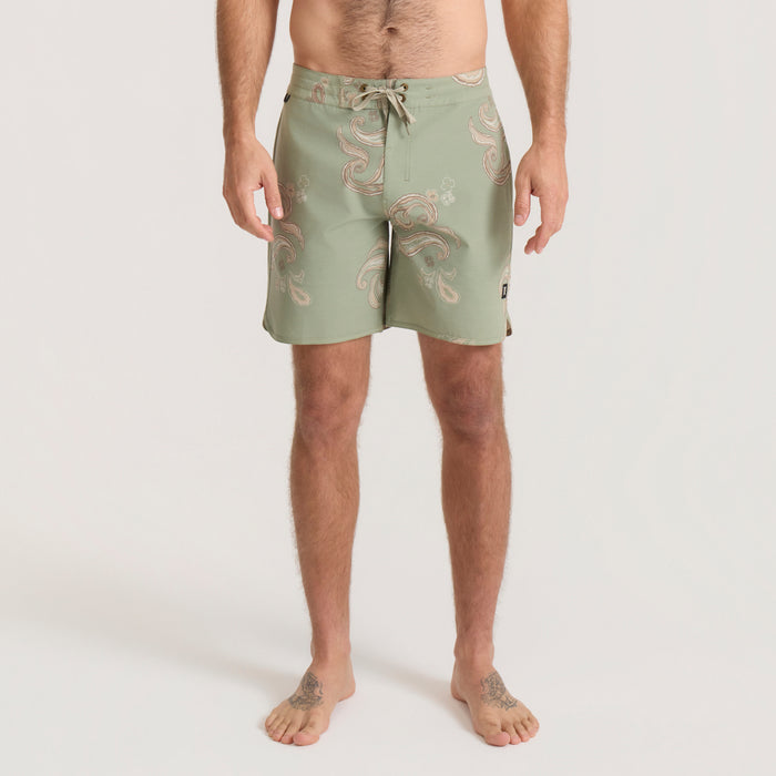 Sage green Chiller Scallop Boardshorts with tan paisley print, worn by man, shown on full-body model from waist down