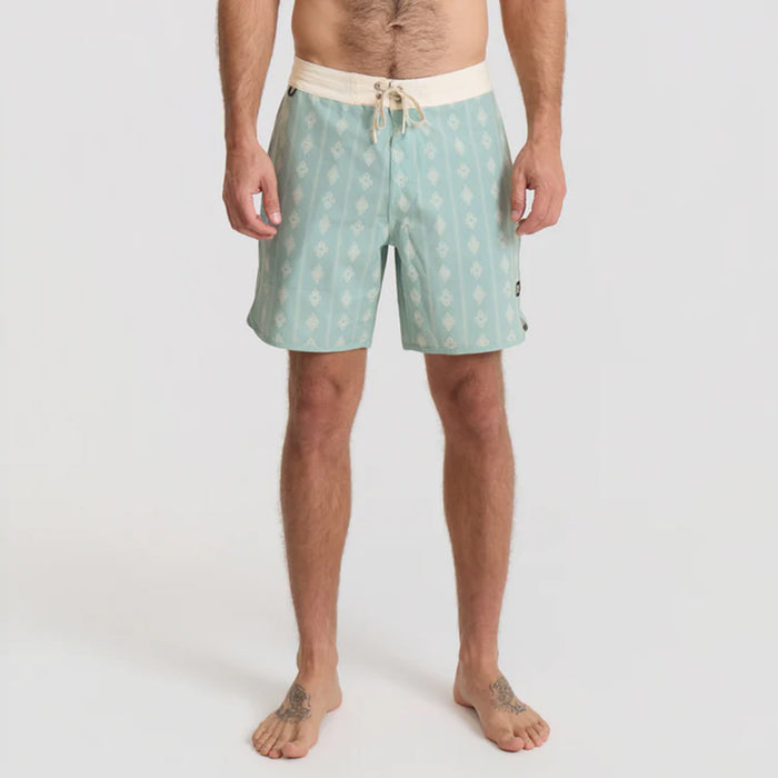 Man in boardshorts standing confidently on a beach, embodying Roark's adventure and outdoor spirit