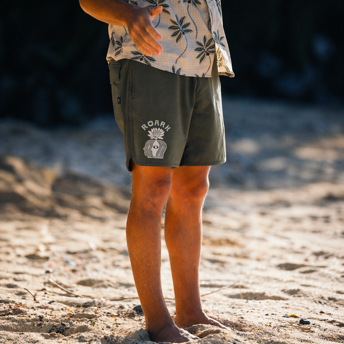 Man wearing versatile boardshorts walking on a serene beach, ideal for active and casual beach adventures.