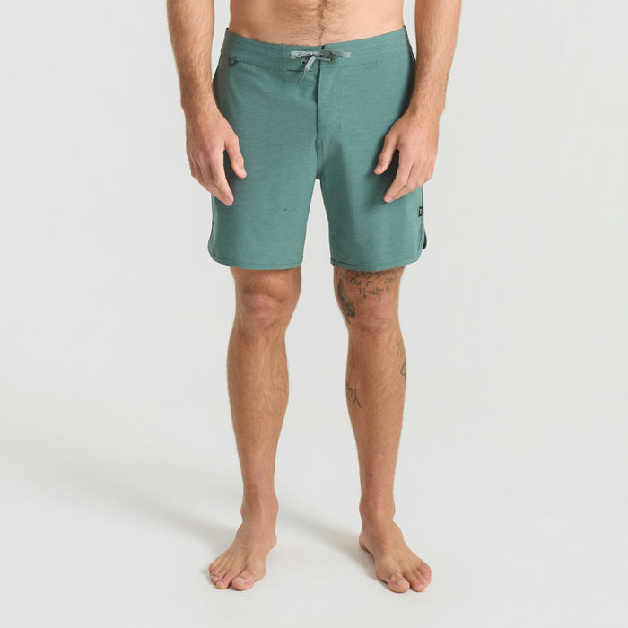 Model showcasing Roark's adventure-ready boardshorts with a barechested look in an outdoor setting, highlighting the versatility and style of the trunks.