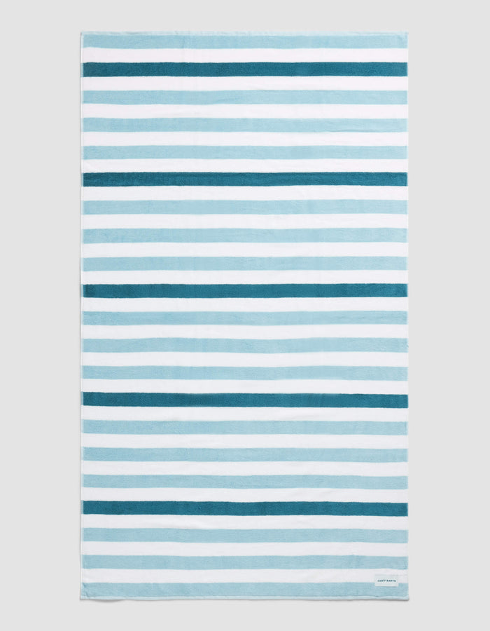 The Cozy Earth Classic Stripe Resort Towel in Lake Stripe features horizontal blue and white stripes of varying thickness and intensity, displayed flat on a neutral background.|Color:Lake Stripe