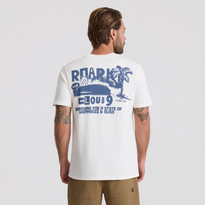 Active shirt by Roark with palm tree background, embodying the spirit of adventure and travel.