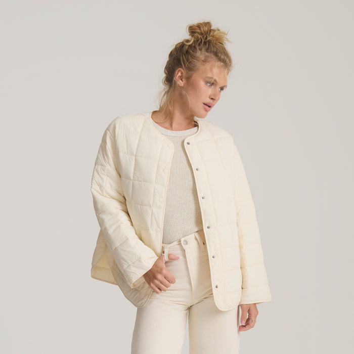 Cloud Liner Jacket in bone worn by model with matching cream pants and ribbed top over neutral background