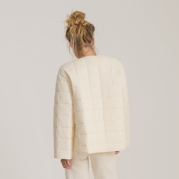 Cloud Liner Jacket in bone quilted material, worn by model shown from back, with vertical stitch detailing