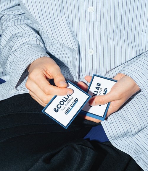 Close up of a person's hands holding two &Collar gift cards